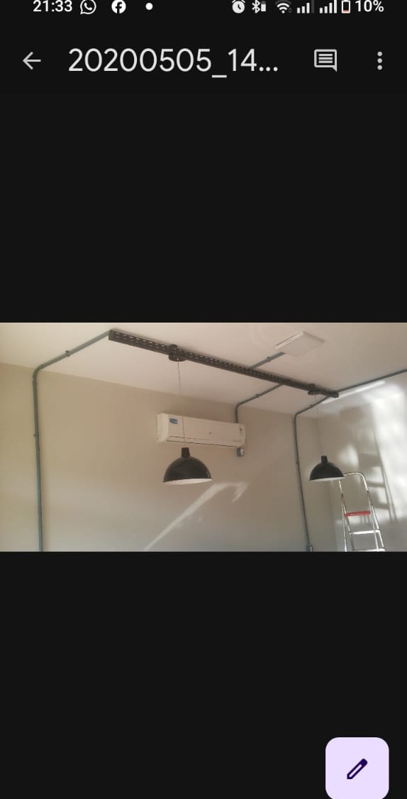 sala com ar-condicionado split no alto e duas luminárias pendentes pretas, com calhas de eletroduto aparentes 